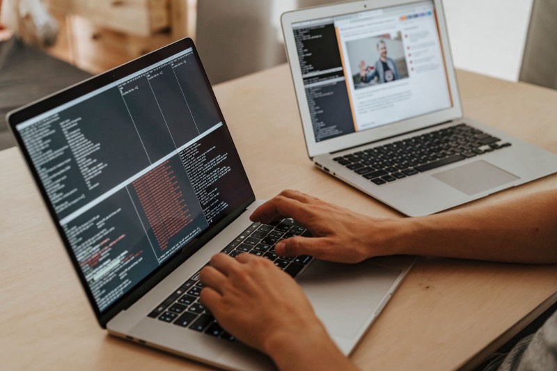 Deux ordinateurs portables, l'un affichant un terminal de code