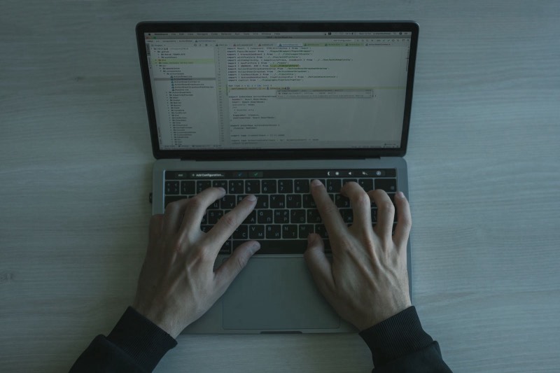 Mains tapant sur un clavier d'ordinateur portable affichant du code
