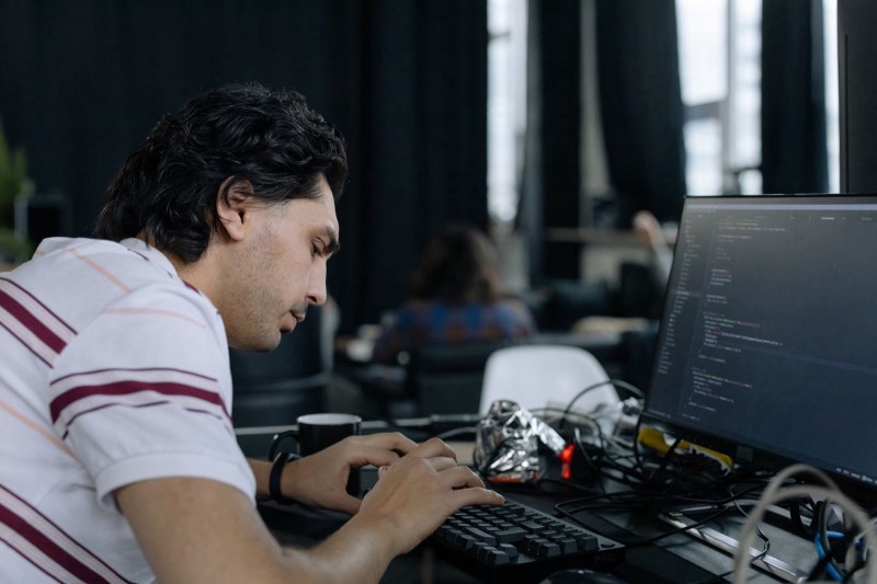 Un homme concentré tape du code sur son ordinateur